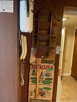 Photo showing wooden mail holder with multiple slots and a wood back scratcher hanging below on a wall, with a fire extinguisher and a wall note partly visible.