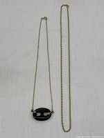 Both necklaces laid side by side on white background showing lengths and pendant detail