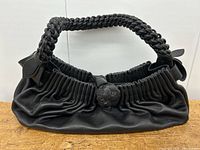 Front view of black leather bag on wooden surface