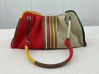 Front view showing red and beige canvas panels with central multi-stripe detail and leather handle.