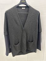 Front view of grey cashmere cardigan with navy sheer silk sleeves on branded hanger