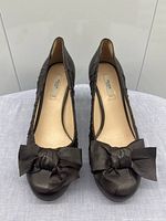 Front view of both shoes showing leather bows and ruched sides