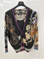 Cardigan layered over camisole, hanging on a black hanger against a white background