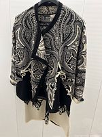 Full front view of jacket and dress on hanger, showing black and cream paisley pattern.
