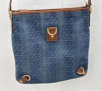 Front view showing GG monogram canvas pattern, brown leather trim, front D-ring tab closure