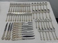 Full layout of forks, spoons, and knives arranged on tablecloth