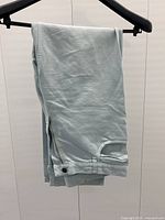 Folded pale blue pants on black hanger, side view