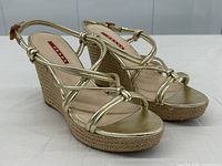 Three-quarter front angle of both sandals showing strappy upper and jute wedge