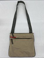 Full front view showing bag shape, adjustable strap, and front zip pocket