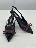 Three-quarter front and side view showing slingback strap, bow detail, and pointed toe shape