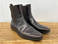 Angled front view of boots on wooden surface showing leather creasing and toe shape