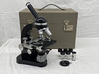 Full view of microscope, eyepieces, objectives, accessories and case in background