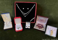 Full collection of jewelry displayed, including earrings, necklaces, Swank tie clip and cufflinks, in original boxes on green background.