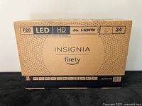 Photo of the boxed Amazon Insignia Fire TV showing brand, series, and features such as LED display, HD resolution, DTS sound, and HDMI compatibility.