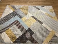 Oblique angle close-up highlighting geometric shapes, colors, and texture of the rug surface.
