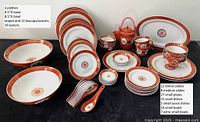 Full assortment of dark orange and white Chinese dinnerware with gold characters including plates, bowls, teapot, teacups, platters, and spoons arranged on black background.