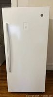 Front view of the upright freezer showing the full white door with handle and GE logo.