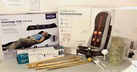 Photo showing all items in the lot including boxed massage mat and massage seat pad, handheld wand, bamboo back scratchers, diffuser set with porcelain container and artificial flowers.