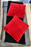 Gray tri-fold mattress with two red pillows on top, showing full mattress surface and pillows' color and texture.