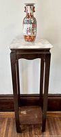 Full frontal view of the mahogany accent table with the porcelain vase on top, showing the full height and design details.
