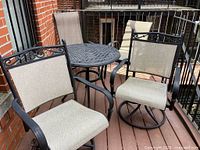 Round cast aluminum table and four coordinating cast aluminum chairs on patio deck.