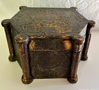 Front angled view of hexagonal carved wooden box showing footed pillar accents and incised decorations