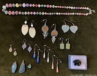 Photo showing full necklace and multiple pairs of earrings arranged flat with pin in box