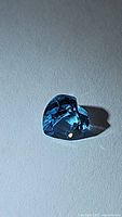Close-up photo of the heart-shaped Swiss blue topaz gemstone showing rich blue color and facets under direct light.