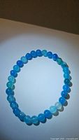 Top view of the circular blue agate bead bracelet with varying blue shades and slight translucency.