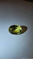 Photo showing natural lemon citrine gemstone oval cut with high luster, sitting on a white background under bright lighting.