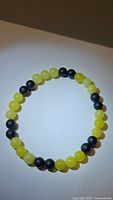 Top view of the stretchy bracelet featuring round beads of natural lemon jade and matt black onyx on a white background.