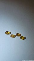 Four oval cut natural yellow sapphires with visible light reflection, showing yellow color with hint of orange.