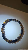 Photo of circular stretchy bracelet composed of polished yellow tigerseye beads showing natural color variation and banding.