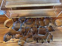 20 metal cookie cutters displayed on a wooden surface, showing various shapes and sizes.