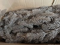 Coiled gold glitter garland strands inside an open cardboard box