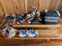 Set of seven fabric Christmas decorations displayed on wooden shelves: includes plush reindeer, embroidered birds, fabric bows with pine cones, and fabric pillow ornaments.