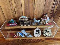 Front angle showing full set of 10 Christmas ornaments on two clear shelves against wooden wall