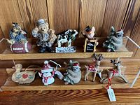 Full set of 10 assorted holiday ornaments arranged on wooden shelves, showing all items in the lot.