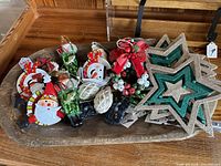 Photo showing a set of Christmas ornaments including character ornaments (Santa, snowman), green and red plastic ornaments, and star-shaped glittery ornaments in beige and green.