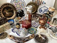 Full view of assortment of souvenirs including plates, tankards, carved figurines, ceramic boxes, and a painted boomerang