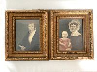 Two framed hand-tinted portraits side by side, one of a man and the other of a woman and child, showing overall condition and style.