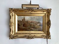 Front view of oil painting in carved giltwood frame with picture light attached