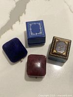 Four antique ring boxes on marble countertop showing size and condition
