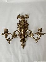 Full view of the solid brass two-arm wall candle sconce showing overall Rococo floral design and symmetrical arms.