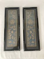 Front view of both framed panels side by side, showing full embroidery and frames