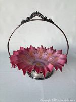 Full view of the Victorian bridal basket showing the silver plated handle and ruffled cranberry glass bowl with hand-enamelled decoration.