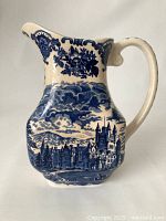 Front side view of the jug showing the blue transferware castle scene and floral decorations.