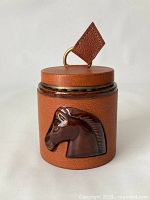 Front view of dispenser showing horse head medallion and leather cover