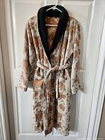 Full view of housecoat hanging on door, showing animal cracker print and black collar.