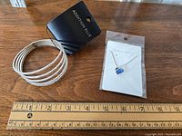 Bracelet and necklace laid on wooden surface with ruler beneath for scale